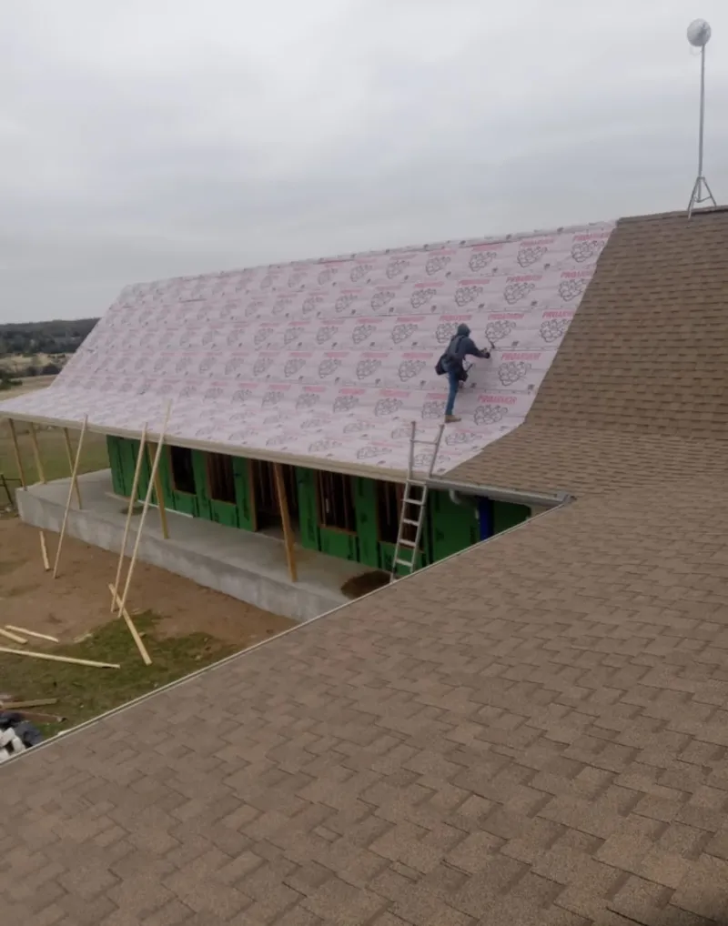 Worker preparing underlayment for a metal roof installation in Wagoner